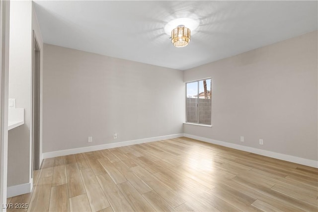 spare room featuring baseboards and light wood-style floors