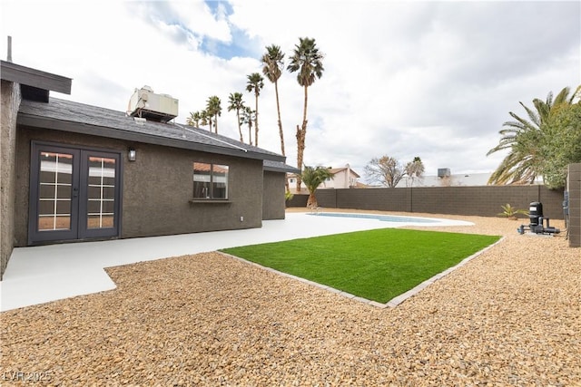 view of yard featuring french doors, a patio, a fenced in pool, and a fenced backyard