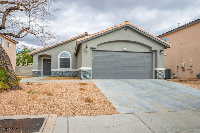 mediterranean / spanish-style house with an attached garage, stone siding, driveway, and stucco siding