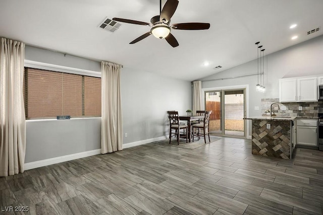 dining space featuring lofted ceiling, baseboards, visible vents, and ceiling fan