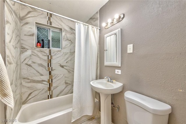 bathroom with toilet, a textured wall, shower / tub combo with curtain, and a sink