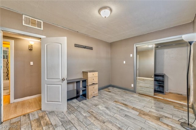 unfurnished office with beverage cooler, visible vents, light wood-style flooring, and baseboards