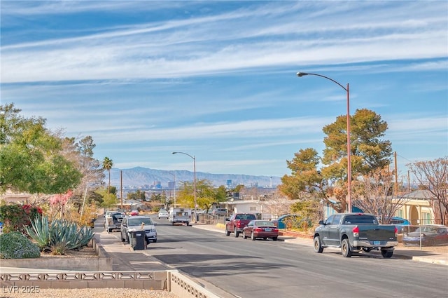 view of street featuring sidewalks, a mountain view, curbs, and street lighting