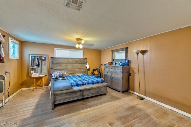 bedroom with baseboards, visible vents, light wood finished floors, and a textured ceiling