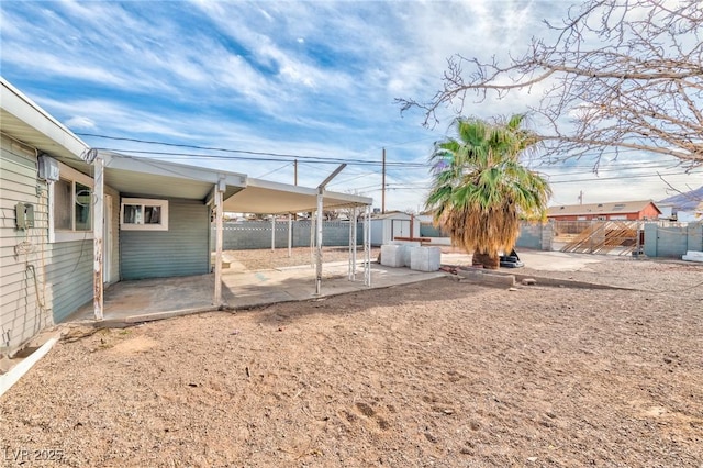 view of yard featuring a patio area, fence, an outdoor structure, and a shed