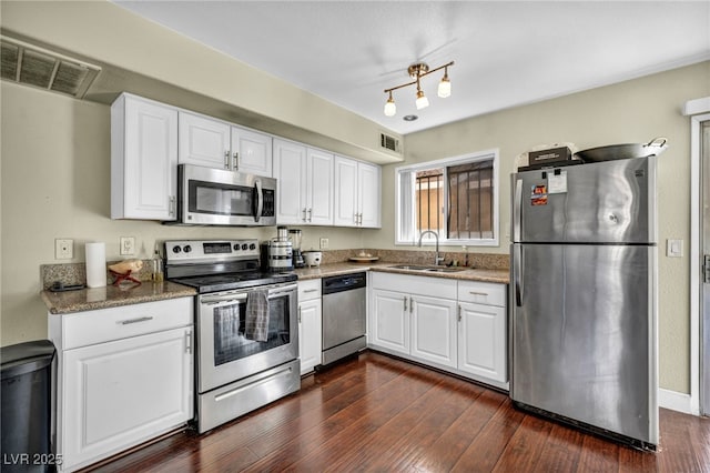 kitchen with a sink, stainless steel appliances, visible vents, and dark wood-style floors