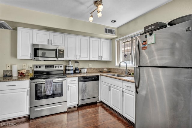 kitchen featuring visible vents, dark wood-style flooring, a sink, stainless steel appliances, and white cabinets