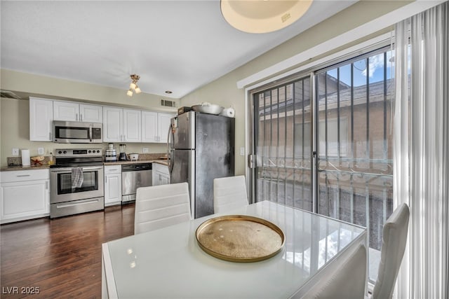 kitchen with dark wood-style floors, visible vents, white cabinets, and appliances with stainless steel finishes