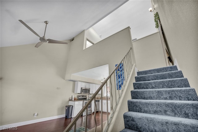 stairway with ceiling fan, baseboards, high vaulted ceiling, and wood finished floors