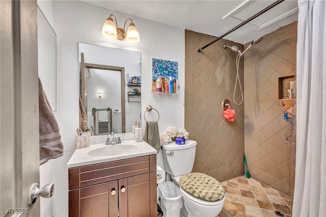 full bathroom featuring tiled shower, toilet, vanity, and a textured wall