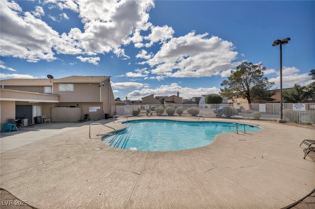 pool with a patio area and fence