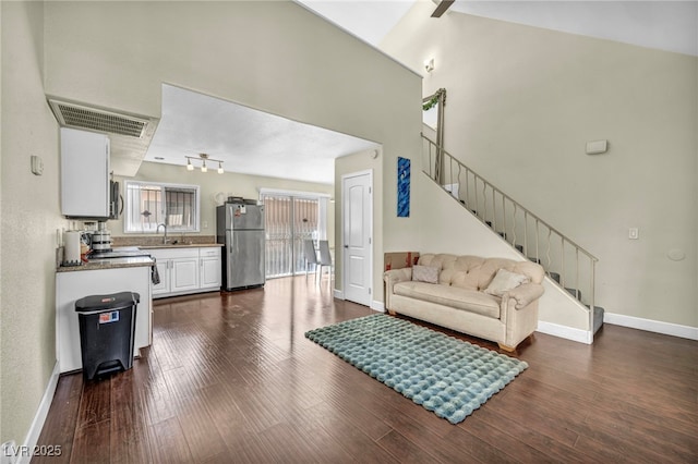 living room with dark wood finished floors, visible vents, stairway, and baseboards