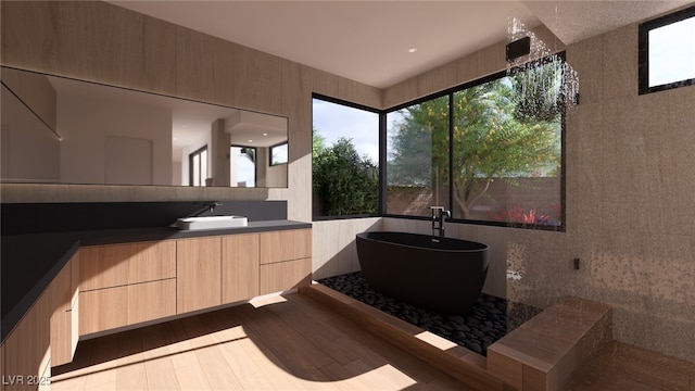 full bathroom with a freestanding bath, wood finished floors, and vanity