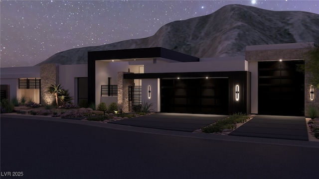 contemporary home featuring stucco siding, a mountain view, and concrete driveway