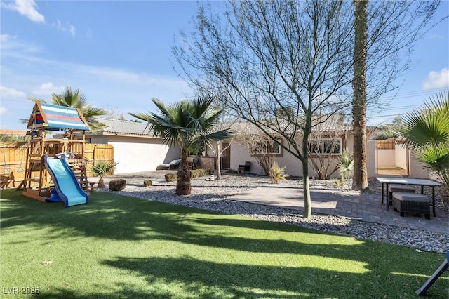 exterior space featuring a playground, fence, and a patio area