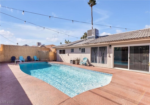 view of swimming pool featuring a patio, central air condition unit, fence, and a fenced in pool