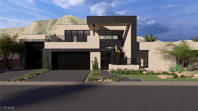 contemporary house with stucco siding, a mountain view, concrete driveway, and a balcony