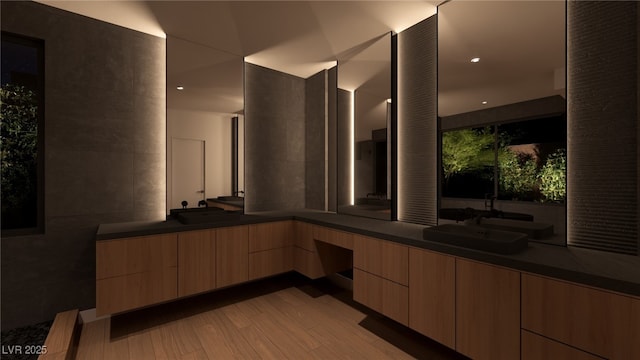 bathroom featuring double vanity, tile walls, wood finished floors, and a sink