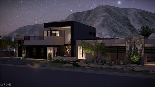 modern home featuring a balcony, a garage, a mountain view, and stucco siding