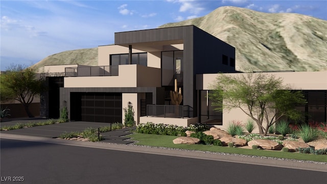 modern home featuring concrete driveway, a balcony, a garage, and a mountain view