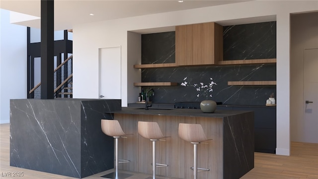 bar featuring tasteful backsplash, light wood-style floors, and a sink