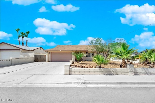 view of front of home with an attached garage, concrete driveway, and fence