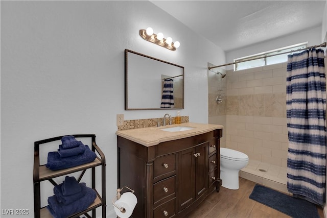 full bathroom featuring vanity, toilet, wood finished floors, and a tile shower