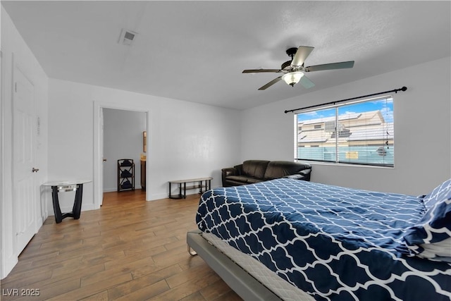 bedroom with ceiling fan, visible vents, baseboards, and wood finished floors