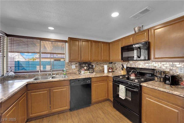 kitchen featuring a sink, visible vents, tasteful backsplash, and black appliances