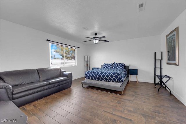 bedroom featuring a ceiling fan, wood finished floors, visible vents, and baseboards