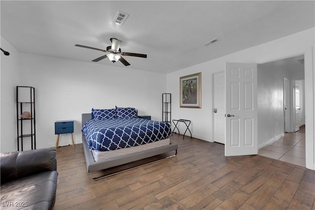 bedroom with a ceiling fan, wood finished floors, visible vents, and baseboards