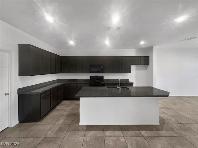 kitchen featuring black appliances, light tile patterned floors, an island with sink, and a sink