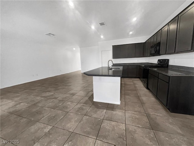 kitchen featuring tile patterned flooring, black appliances, a kitchen island with sink, and a sink