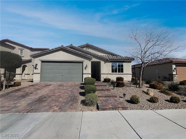 single story home with stucco siding, a tile roof, decorative driveway, and a garage