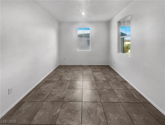 tiled spare room featuring baseboards