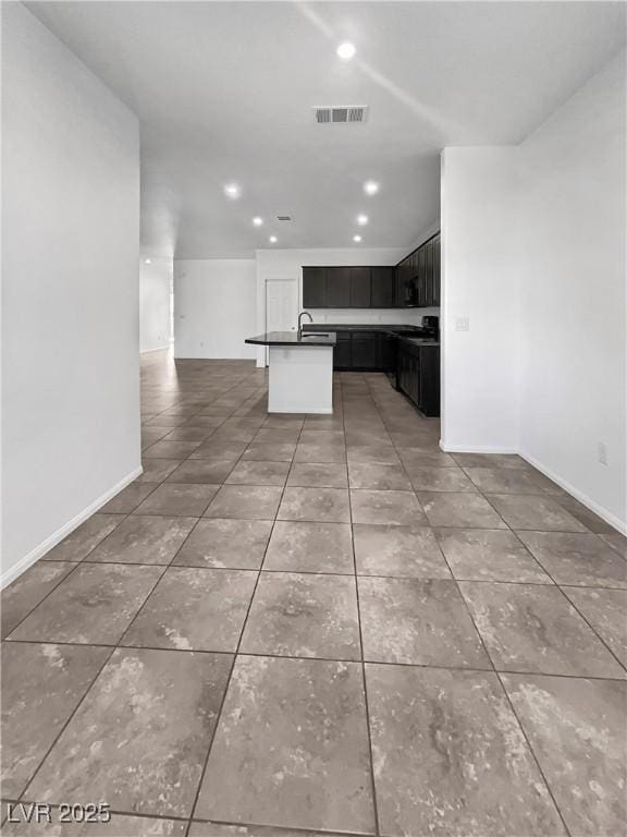 kitchen featuring dark cabinetry, visible vents, a sink, dark countertops, and open floor plan