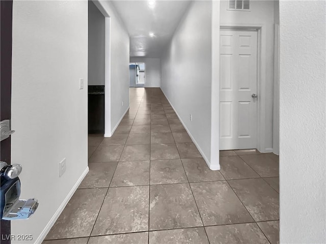 corridor with tile patterned flooring, visible vents, and baseboards