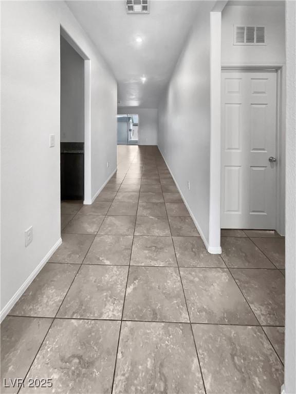 corridor with tile patterned flooring, visible vents, and baseboards