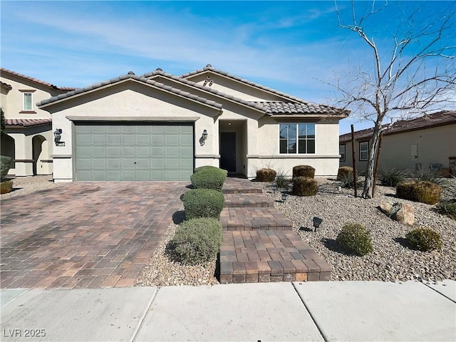 view of front of house with stucco siding, an attached garage, a tile roof, and decorative driveway