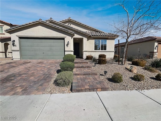 single story home with stucco siding, an attached garage, a tile roof, and decorative driveway