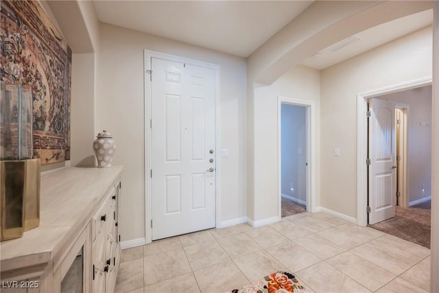 entryway featuring visible vents, arched walkways, baseboards, and light tile patterned flooring