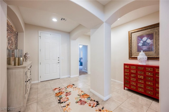 foyer with light tile patterned floors, visible vents, arched walkways, and baseboards