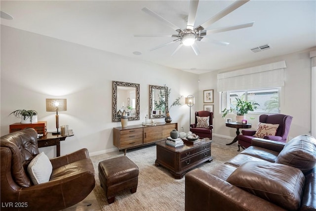 living area with visible vents, baseboards, light colored carpet, and ceiling fan