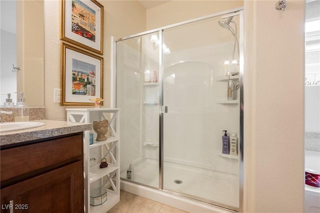 bathroom featuring tile patterned flooring, a stall shower, and vanity