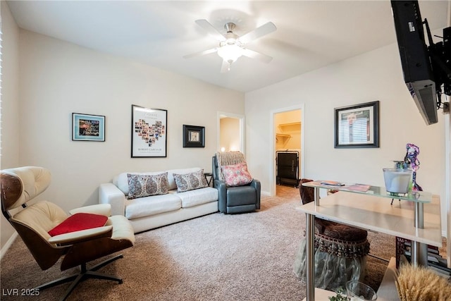 carpeted living room featuring baseboards and a ceiling fan