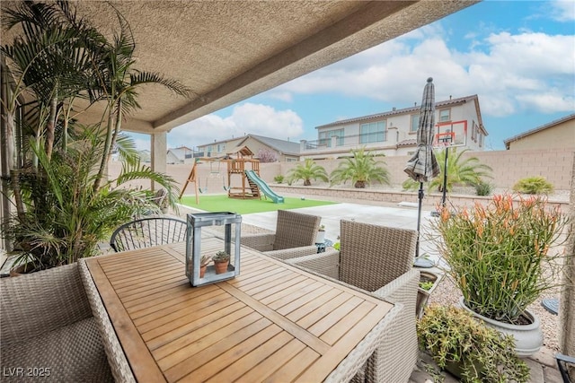 view of patio with outdoor dining area, a fenced backyard, and a playground