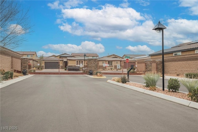 view of road with traffic signs, curbs, a gate, a gated entry, and a residential view