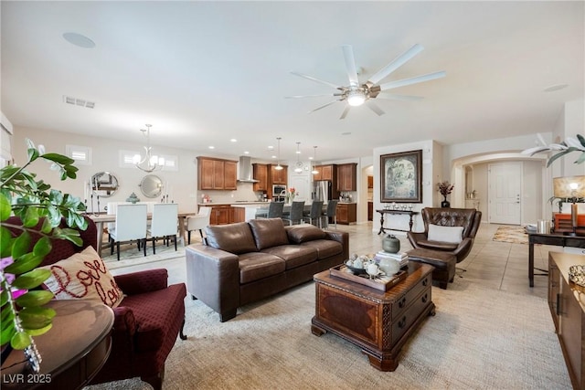 living area featuring light tile patterned floors, visible vents, recessed lighting, arched walkways, and ceiling fan with notable chandelier