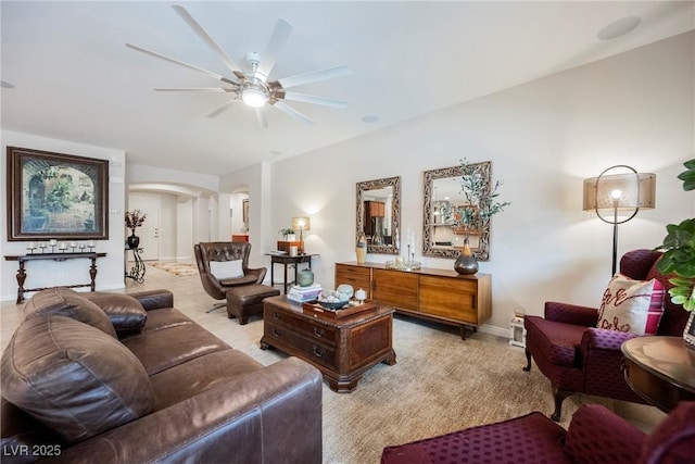 living area featuring arched walkways, baseboards, and a ceiling fan