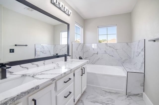 bathroom featuring double vanity, a sink, marble finish floor, and a garden tub